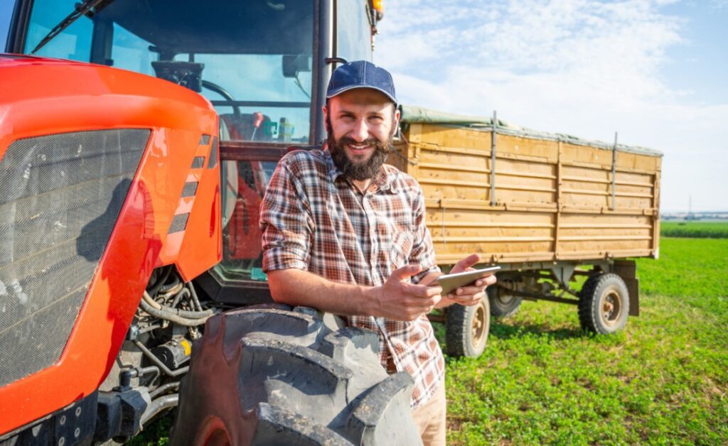Homme tenant une tablette et s'appuyant sur son tracteur
